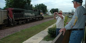 two men looking at train as it goes by